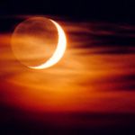 Un fin voile nuageux masque le croissant lunaire surexposé, mais laisse voir la lumière cendrée, cette pâle lueur qui suffit à éclairer la surface lunaire normalement plongée dans l’obscurité. On y distingue faiblement mers et cratères.