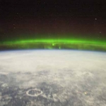 Aurores polaires au-dessus du Canada avec le cratère d’impact du Manicouagan au premier plan. Les nuages et la surface de notre planète sont illuminés par le clair de Lune.