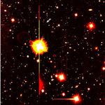 Un des plus lointains sursauts gamma jamais détecté, GRB 000131, à 11 milliards d’années-lumière. D’abord signalé par la sonde Ulysse le 31 janvier 2000, puis observé par le télescope Européen géant VLT. Il est à peine visible, au bout de la petite flèche blanche en haut de l’image. La brillante tache de lumière avec aigrette à la gauche de l’image est en fait une étoile de notre galaxie en premier plan.