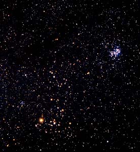 L\'étoile Aldébaran est la plus brillante de ce cliché pris dans la constellation du Taureau, l\'amas des Hyades forme un V dont Aldébaran constitue un sommet. Le petit groupe d\'étoiles bleues (en haut à droite) est l\'amas des Pléiades.