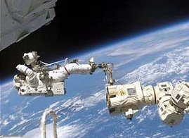 L’homme et le robot travaillant pied dans la pince. L’astronaute Jerry Ross flotte au-dessus de l’atmosphère terrestre, attaché à une extrémité du bras robotique Canadarm2 L’homme et le robot travaillant pied dans la pince. L’astronaute Jerry Ross flotte au-dessus de l’atmosphère terrestre, attaché à une extrémité du bras robotique Canadarm2