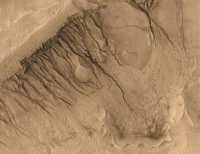A l’intérieur de la dépression de Newton, d’étroits chenaux serpentent du sommet jusqu’au sol. Ces « ravines » et bien d’autres ont été observées pour la première fois sur des images haute résolution prises par Mars Global Surveyor.