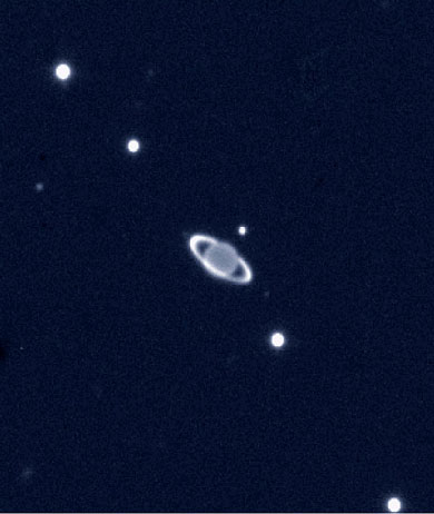 Non, ce n’est pas Saturne ! Il s’agit d’Uranus photographiée en infrarouge par l’un des télescopes du VLT. A cette longueur d’onde, ses anneaux sont aussi brillants que son disque planétaire. Notons que le diamètre apparent d’Uranus est minuscule : à peine 3,5 secondes d’arc ! Les points qui entourent Uranus sont ses satellites (voir photo suivante).