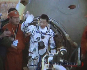 Yang Liwei sort de la capsule et salue l’équipe de récupération debout. Peu après, il sera placé sur une chaise, conformément aux procédures habituelles.