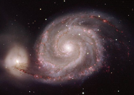 Les nébuleuses rouges réparties le long des bras de la galaxie des Chiens de Chasse sont des nuages d’hydrogène ionisé appelé régions H II. De ces nébuleuses naissent et naîtront de très nombreuses étoiles.